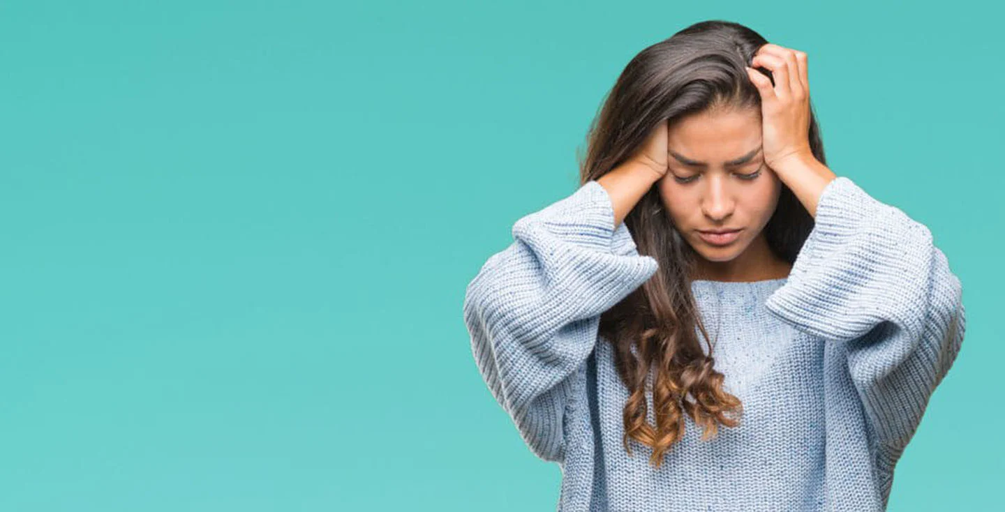 Woman holding her hands to her head indicating she has a migraine