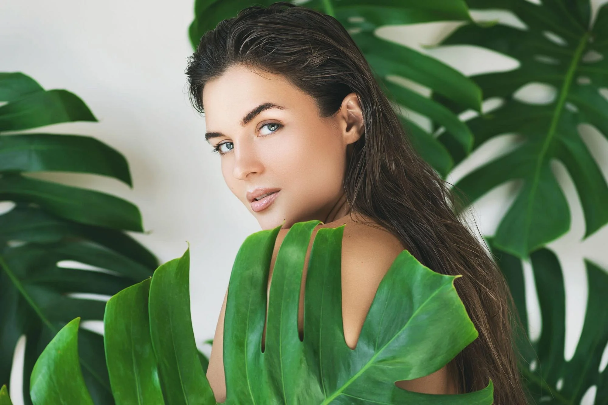 Woman posing behind tropical plants | Highest rated Bellevue Facial Plastic Surgeon - Yirae Ort M.D.